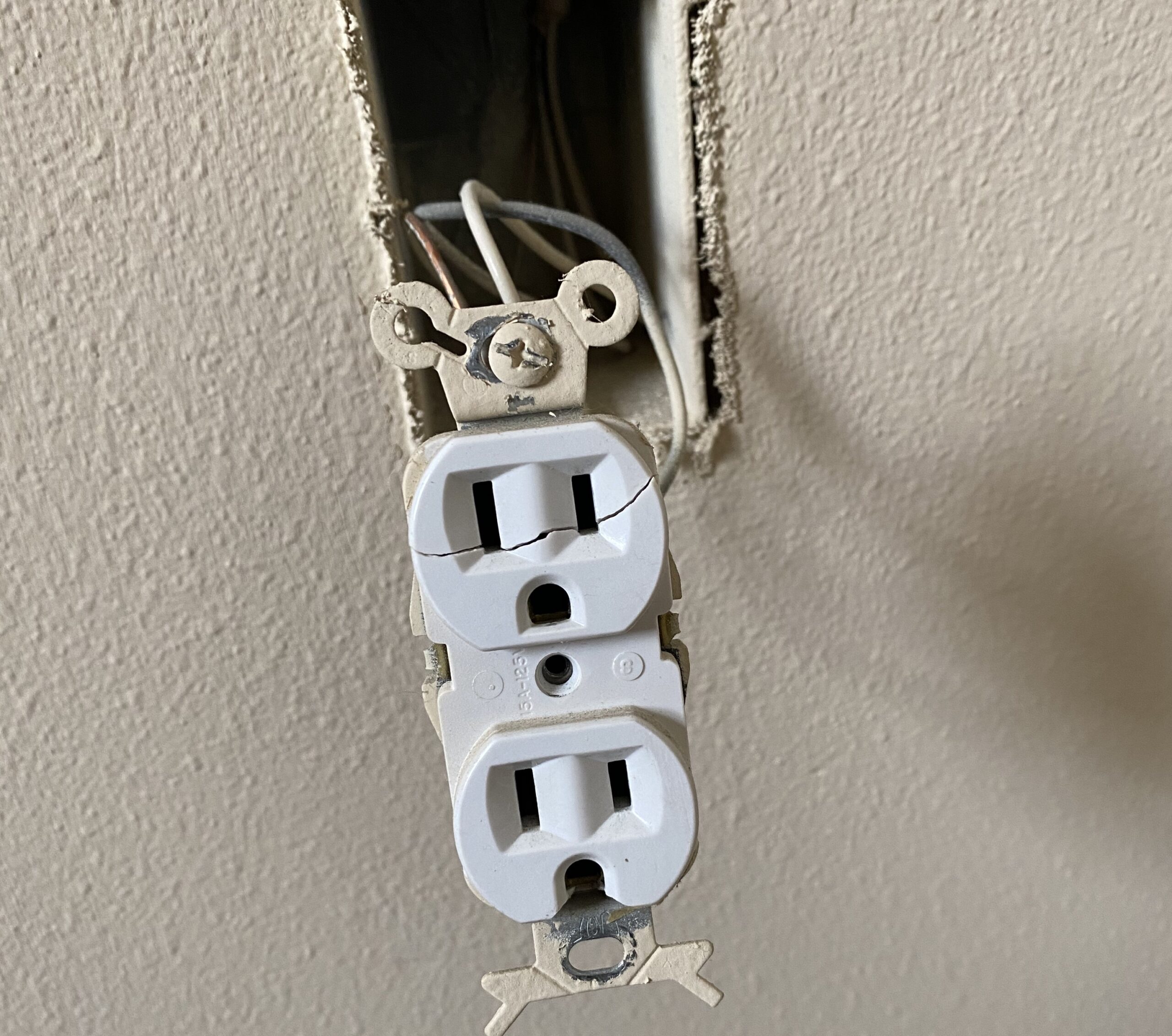 A cracked outlet pulled from wall socket