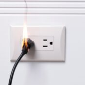 Burning electrical outlet with fire damage on power cord