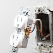 Exposed electrical outlet showing loose wiring and faulty installation