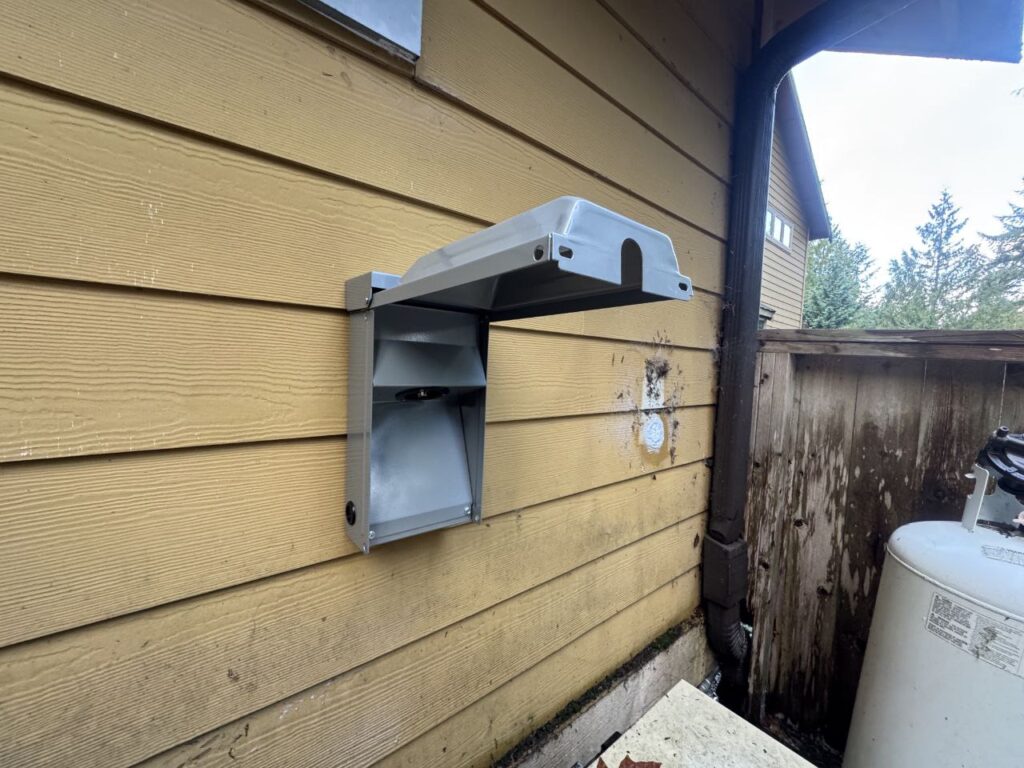 Outdoor generator inlet box installed on home exterior for safe portable generator hookup and backup power