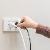 Person plugging a device into a wall outlet while troubleshooting multiple outlets not working