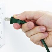 Person plugging in a cord into a wall outlet — potential spark risk