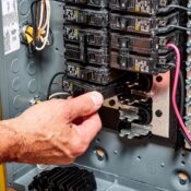 Licensed electrician replacing a tripped circuit breaker in a Seattle home electrical panel