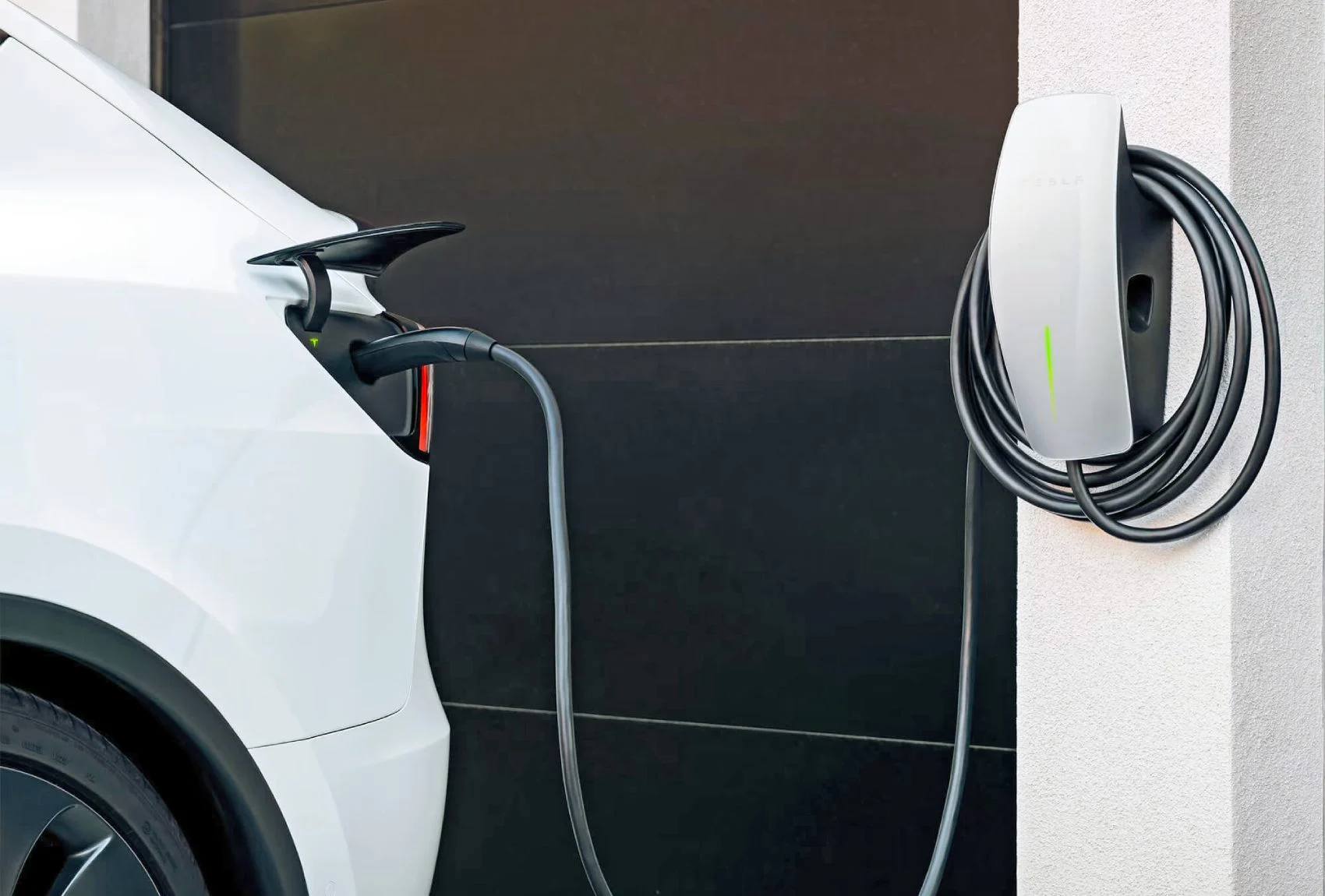Tesla vehicle charging at home using a wall-mounted Tesla wall connector installed by a licensed electrician